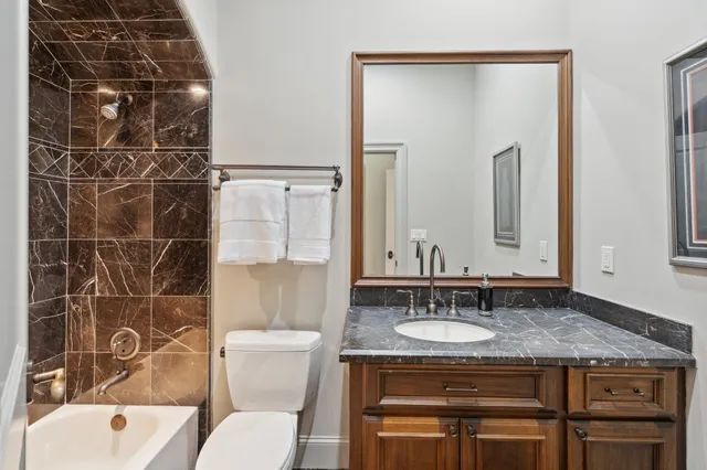 a bathroom with a granite countertop sink a toilet and shower