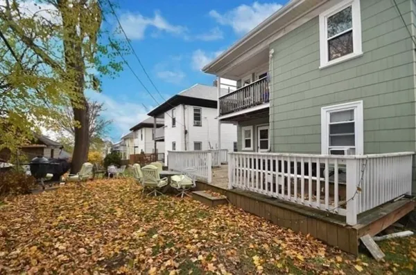 a view of a house with a wooden bench in a yard