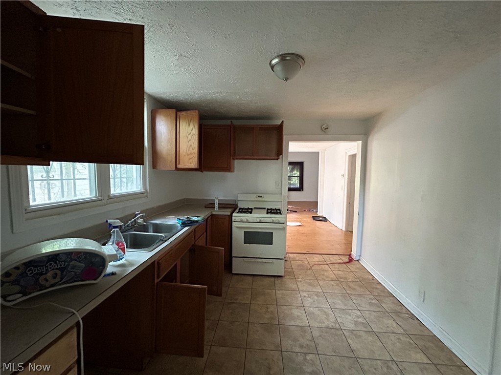 7723 Spafford Road Cleveland, OH 44105 - Photo 7 of 14 Kitchen featuring sink, light tile patterned flooring, gas range gas stove, and a textured ceiling