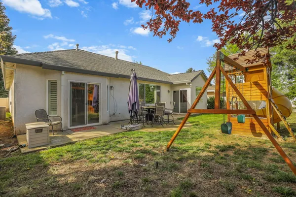 a view of backyard with a slide and swing