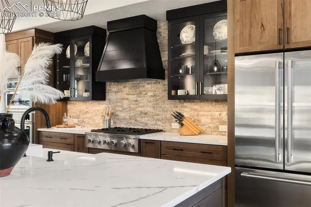 a kitchen with stainless steel appliances granite countertop a refrigerator a stove and a sink with wooden floor