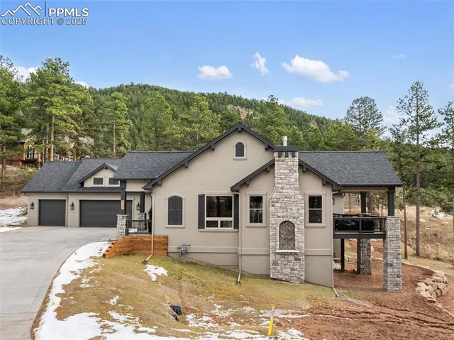 a view of a white house with a yard plants and large tree