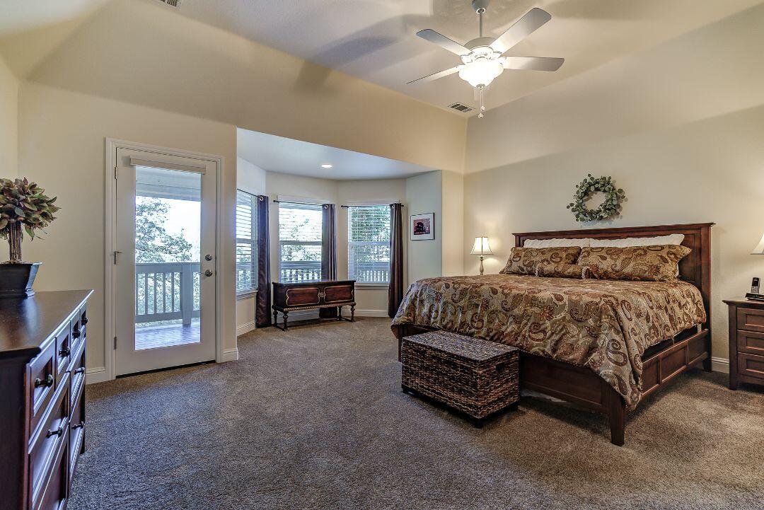 380 Franciscan Trail Redding, CA 96003 - Photo 25 of 78 a spacious bedroom with a bed a chandelier and a flat tv screen on dresser