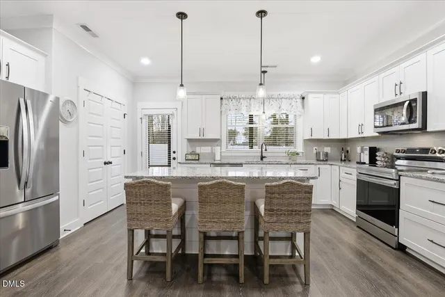 a kitchen with stainless steel appliances granite countertop a stove a refrigerator a oven a sink a dining table and chairs