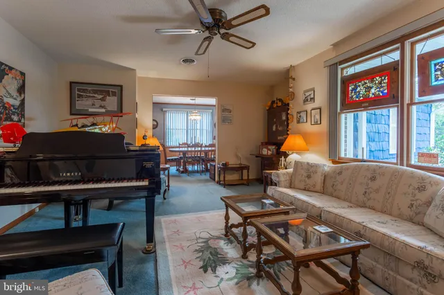 a living room with furniture a piano and a window