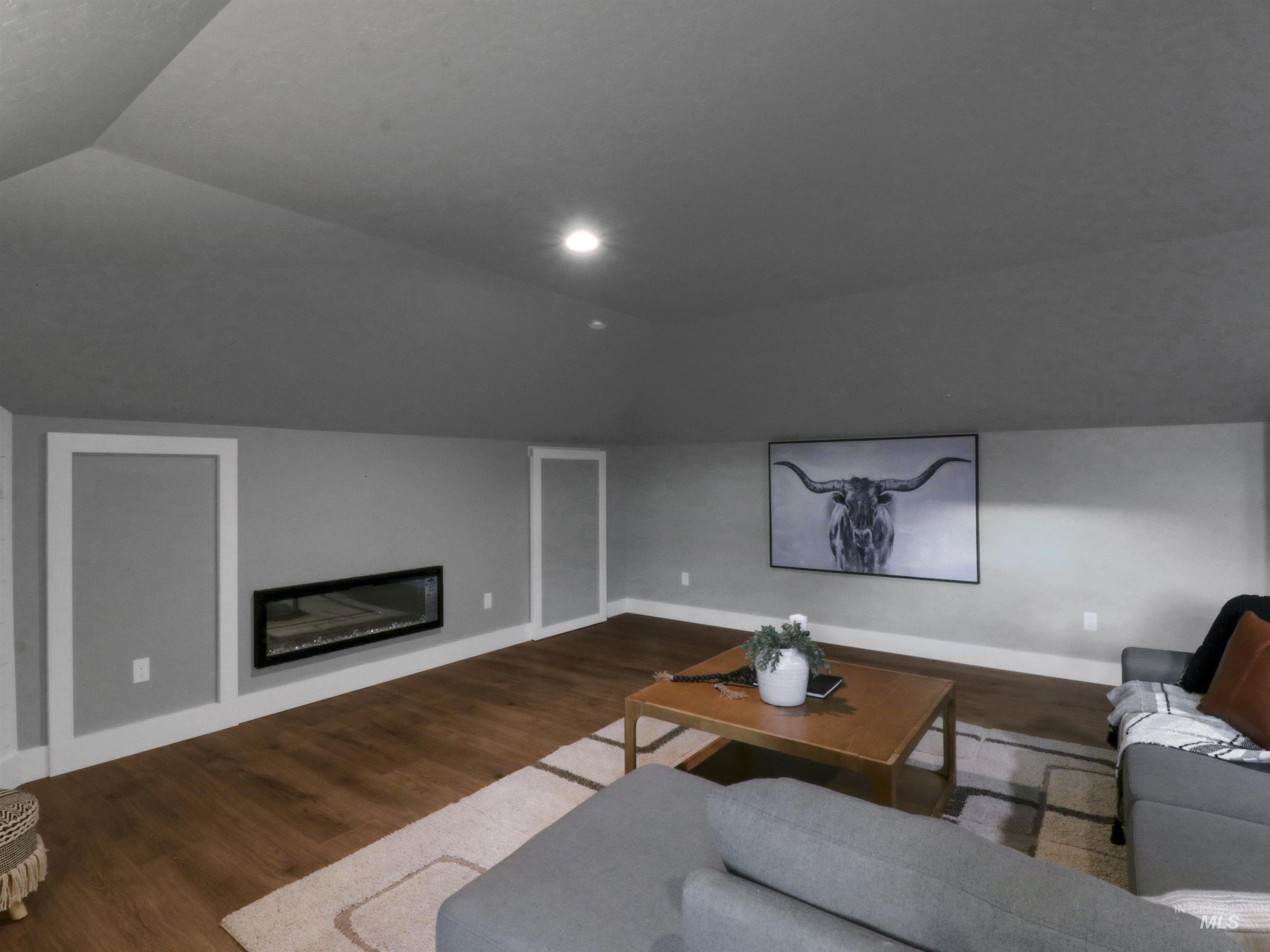 8991 Edna Lane Middleton, ID 83644 - Photo 28 of 50 Living area with wood finished floors, a glass covered fireplace, vaulted ceiling, and recessed lighting