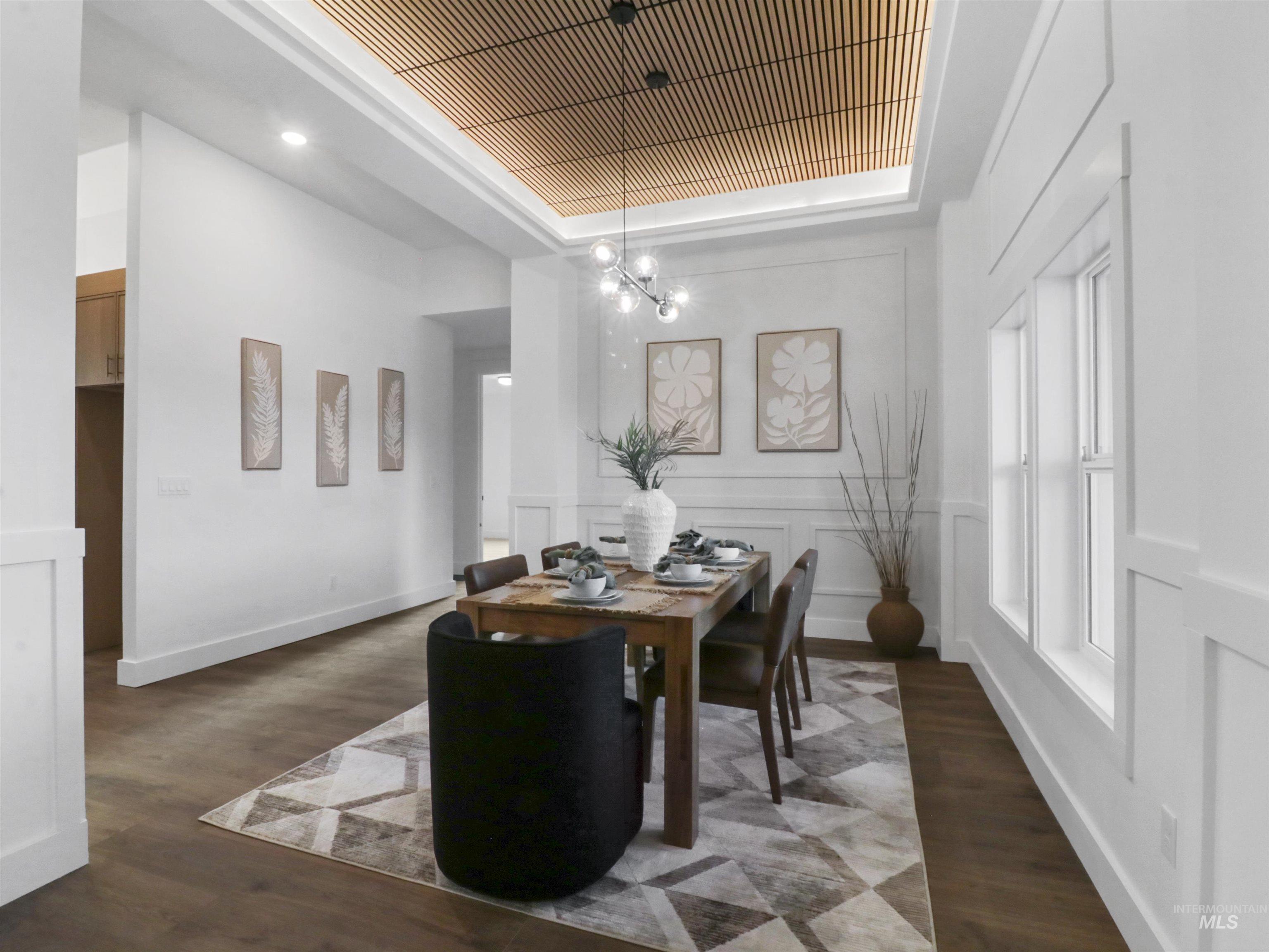 8991 Edna Lane Middleton, ID 83644 - Photo 10 of 50 Dining space featuring wood finished floors, a tray ceiling, a chandelier, a decorative wall, and wainscoting
