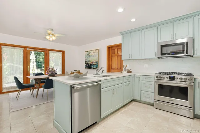 a kitchen with a stove top oven a sink dishwasher a dining table and chairs with wooden floor