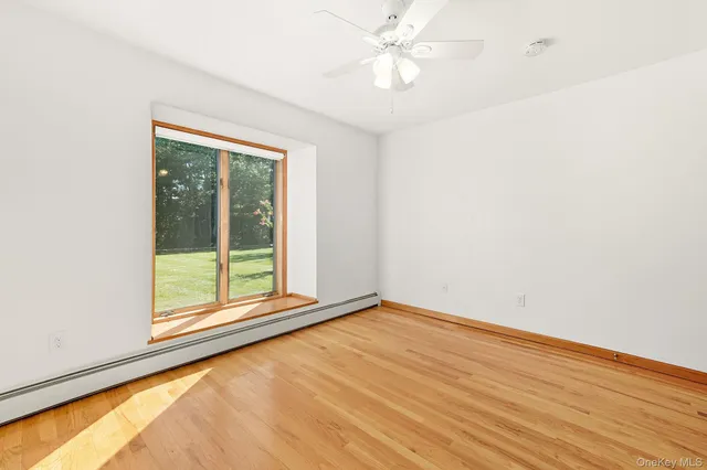 an empty room with wooden floor fan and windows