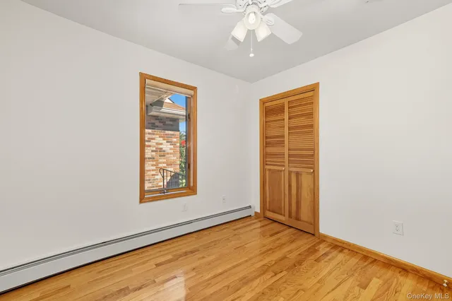 an empty room with wooden floor chandelier fan and windows