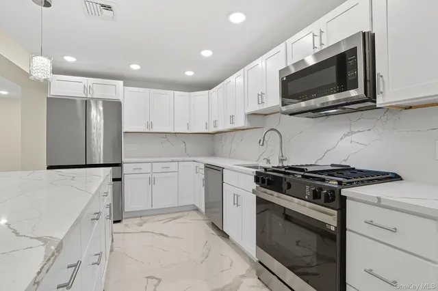 a kitchen with stainless steel appliances kitchen island granite countertop a refrigerator and a stove top oven