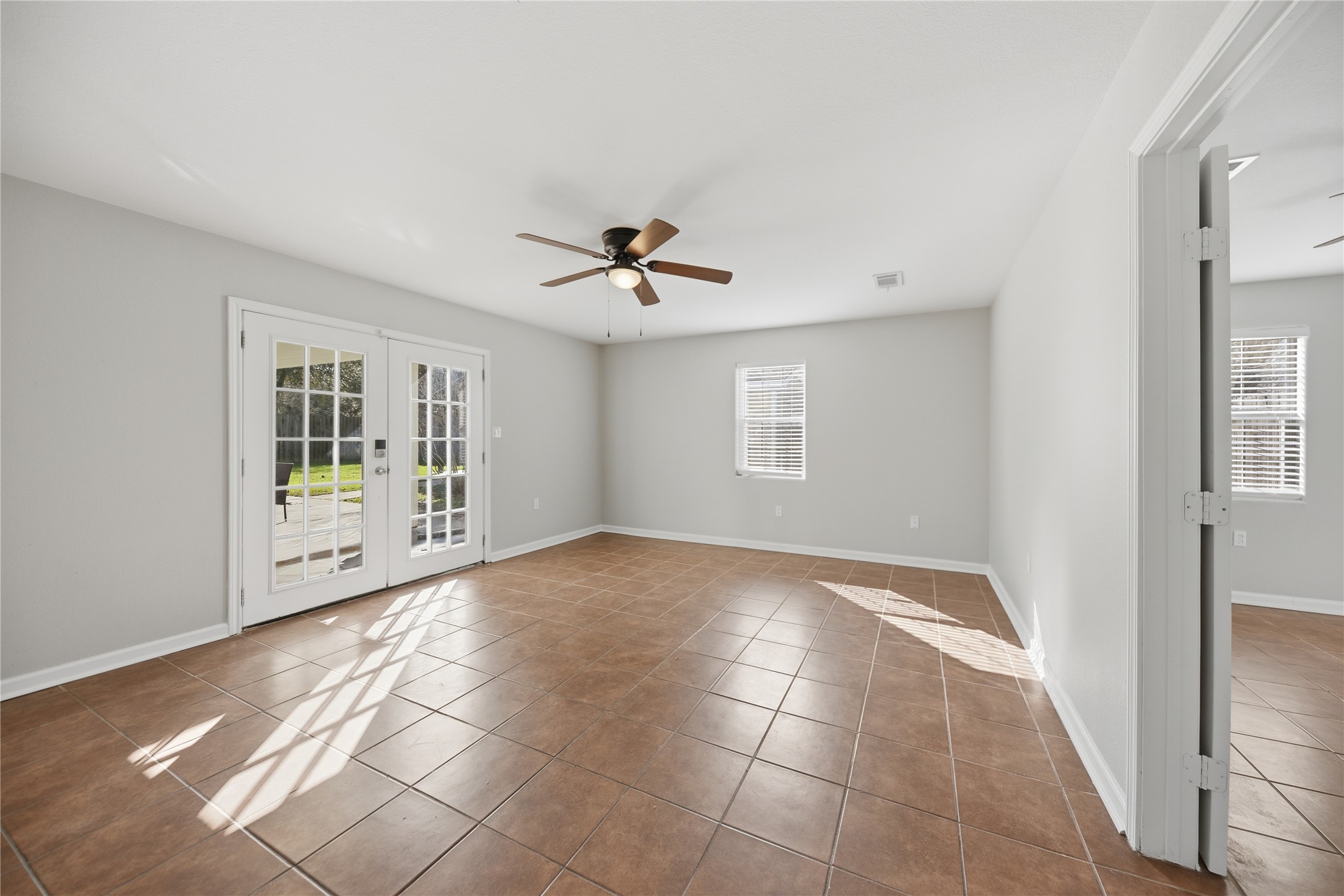 1702 Rampart Street Columbus, TX 78934 - Photo 21 of 38 Empty room with french doors, tile patterned flooring, and a ceiling fan