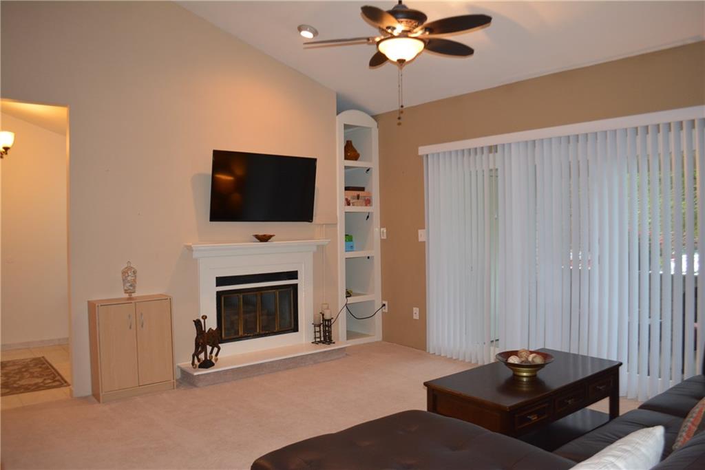 Living Room with wood burning fireplace and cathedral ceilings. Lighted ceiling fan, recessed lighting, sliding glass door leading the deck.