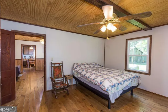 a bedroom with a bed and a dresser with wooden floor