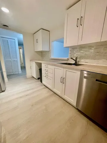 a kitchen with granite countertop white cabinets and sink