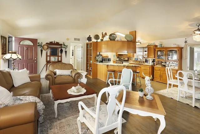 a living room with furniture kitchen view and a wooden floor