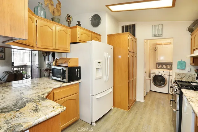 a kitchen with stainless steel appliances granite countertop a refrigerator a stove and a sink with wooden floor