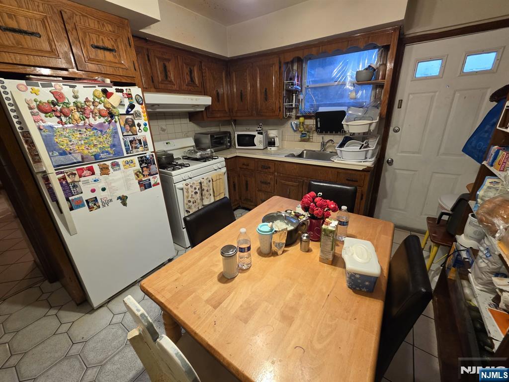 32 Elm Street Paterson, NJ 07501 - Photo 15 of 20 a kitchen with stainless steel appliances kitchen island granite countertop a sink dishwasher and a refrigerator with wooden cabinets