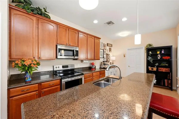 a kitchen with stainless steel appliances granite countertop a refrigerator sink stove microwave and cabinets