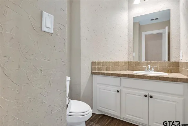a bathroom with a granite countertop toilet sink and mirror