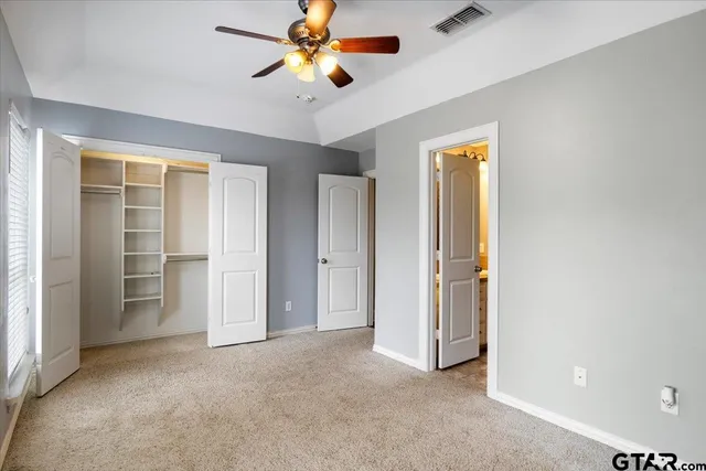 an empty room with closet and a chandelier fan