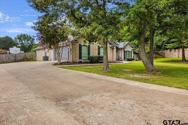 a tree in front of a house next to a yard