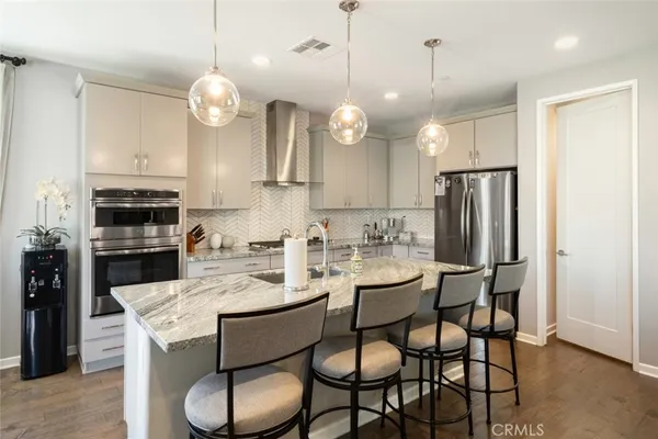 a kitchen with stainless steel appliances a stove a refrigerator a microwave a dining table and chairs