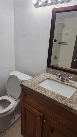 a bathroom with a granite countertop toilet a sink and a mirror