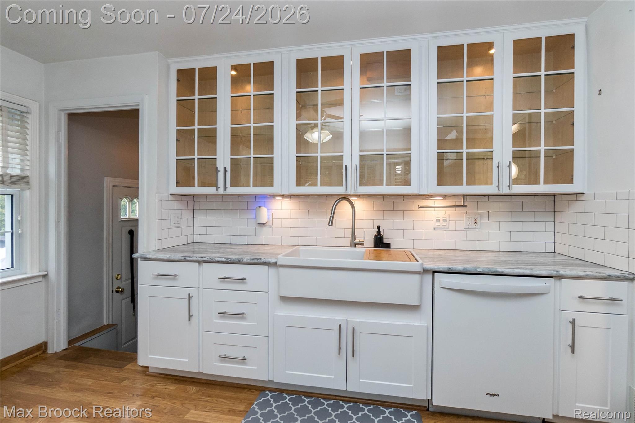 1090 Cambridge Road Berkley, MI 48072 - Photo 8 of 43 Kitchen featuring white shaker cabinetry, glass-front upper cabinets with interior lighting, subway tile backsplash, white farmhouse sink, and wood-finish flooring