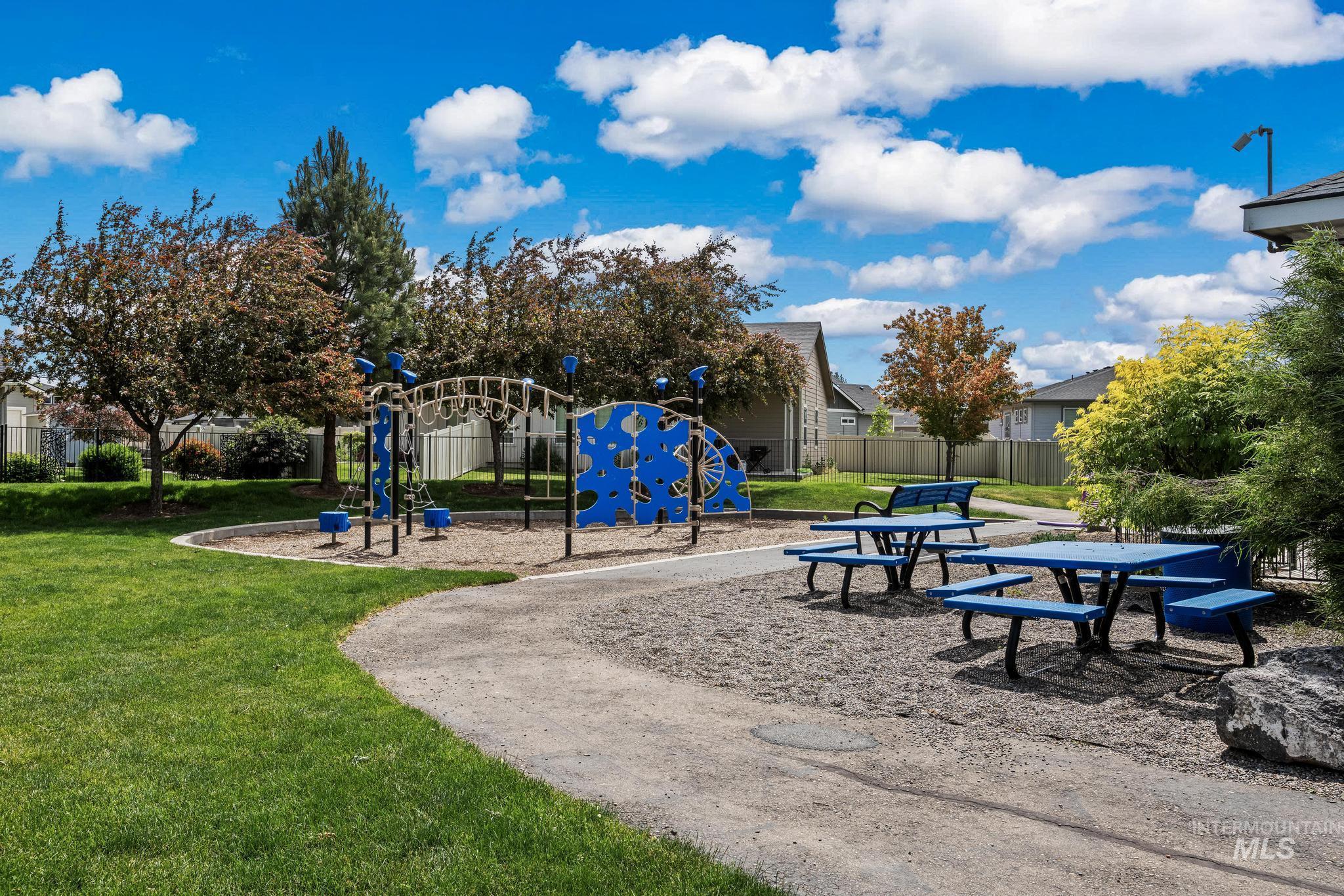 2681 East Rhyolite Court Nampa, ID 83686 - Photo 42 of 48 Community park area featuring a blue and black playground structure, multiple blue picnic tables, a blue park bench, and mature trees