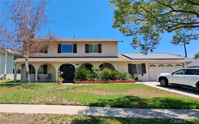 a view of a white house with a big yard and large trees