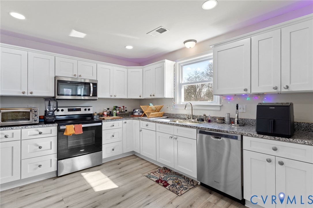 7547 Media Park Road Henrico, VA 23231 - Photo 10 of 24 a kitchen with granite countertop white cabinets sink and stainless steel appliances