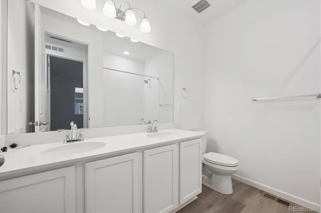 a bathroom with a toilet a sink a mirror and vanity