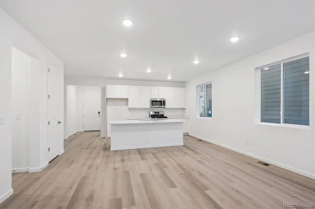 a view of a kitchen with cabinets stainless steel appliances wooden floor and a window