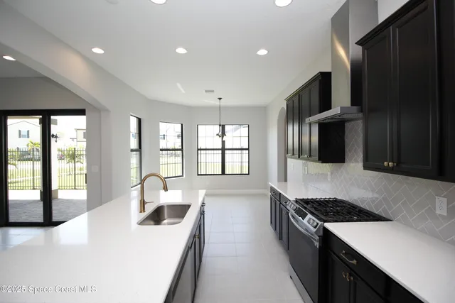 a large kitchen with stainless steel appliances kitchen island a large counter top a stove and a sink