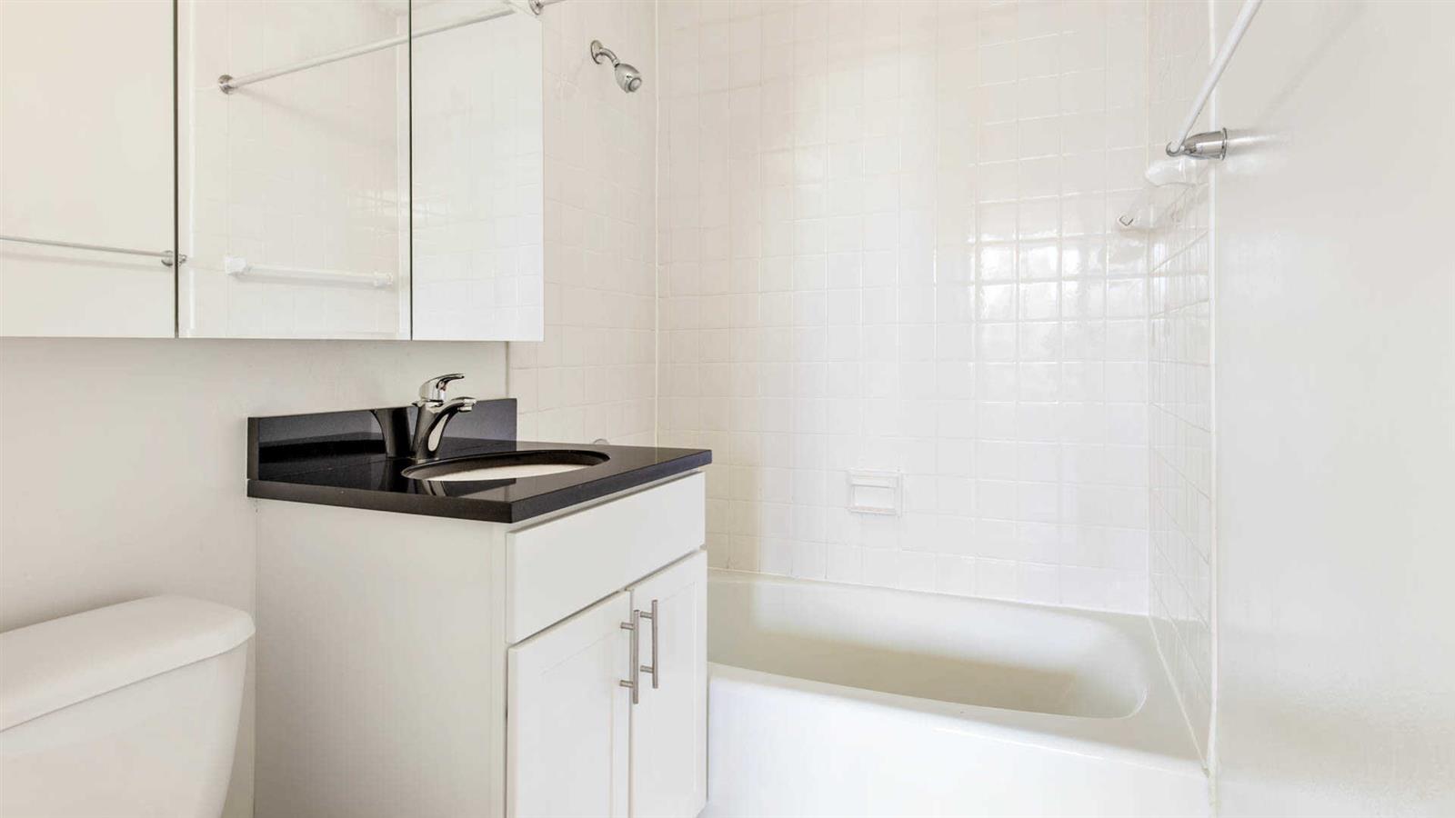 245 East 40th Street, Unit 24J Manhattan, NY 10016 - Photo 7 of 10 a white bath tub sitting next to a sink