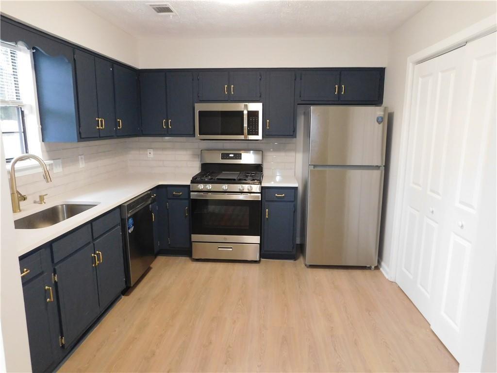 3589 North Hopkins Court Powder Springs, GA 30127 - Photo 10 of 17 a kitchen with a refrigerator sink and wooden cabinets