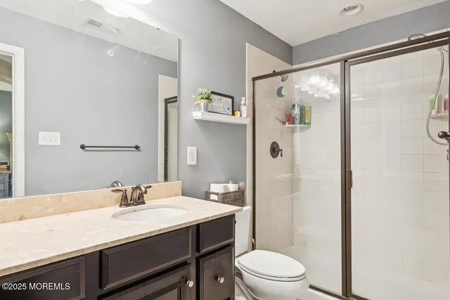 a bathroom with a granite countertop sink toilet a large mirror a shower and a mirror