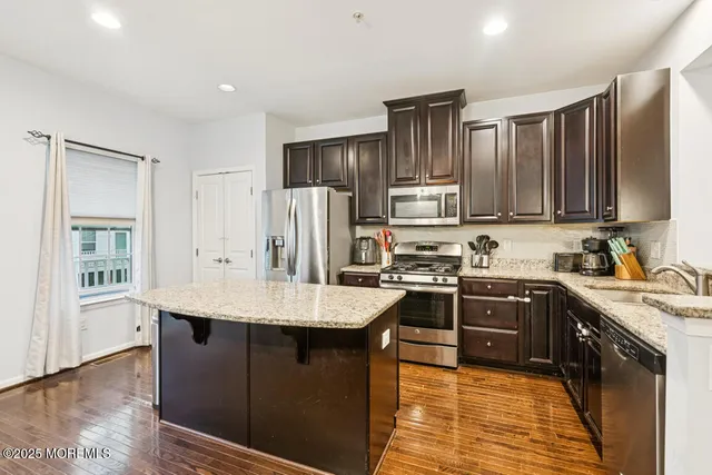 a kitchen with kitchen island granite countertop a sink stove and refrigerator