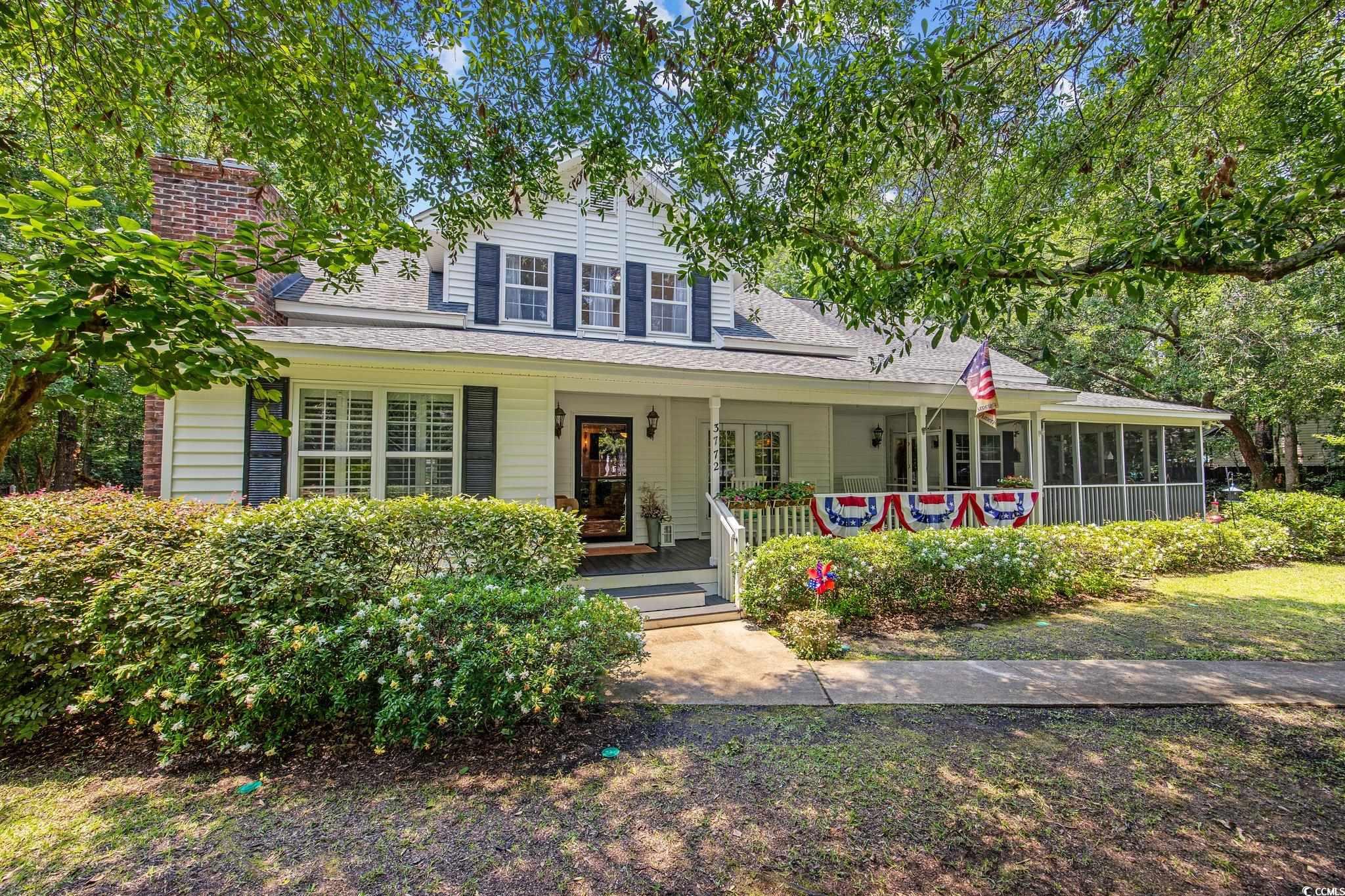 View of front of house with covered porch, a shingled roof, and a sunroom