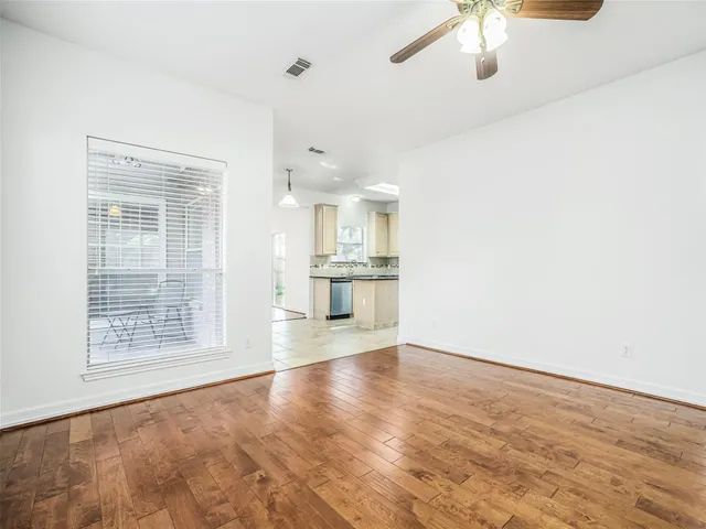 an empty room with wooden floor fan and windows