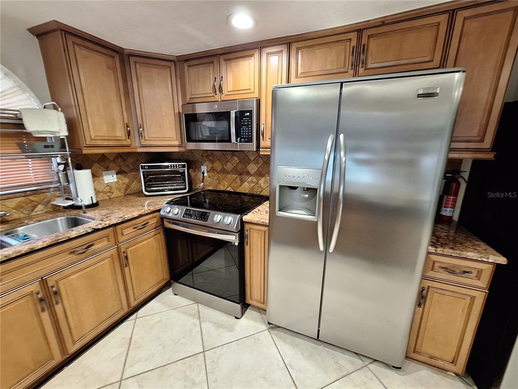 9415 Indale Drive New Port Richey, FL 34654 - Photo 18 of 93 a kitchen with granite countertop a refrigerator stove and microwave