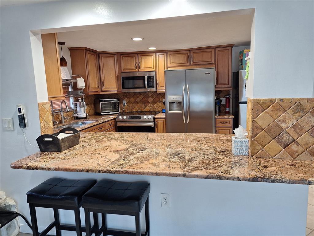 9415 Indale Drive New Port Richey, FL 34654 - Photo 20 of 93 a kitchen with granite countertop a refrigerator and microwave