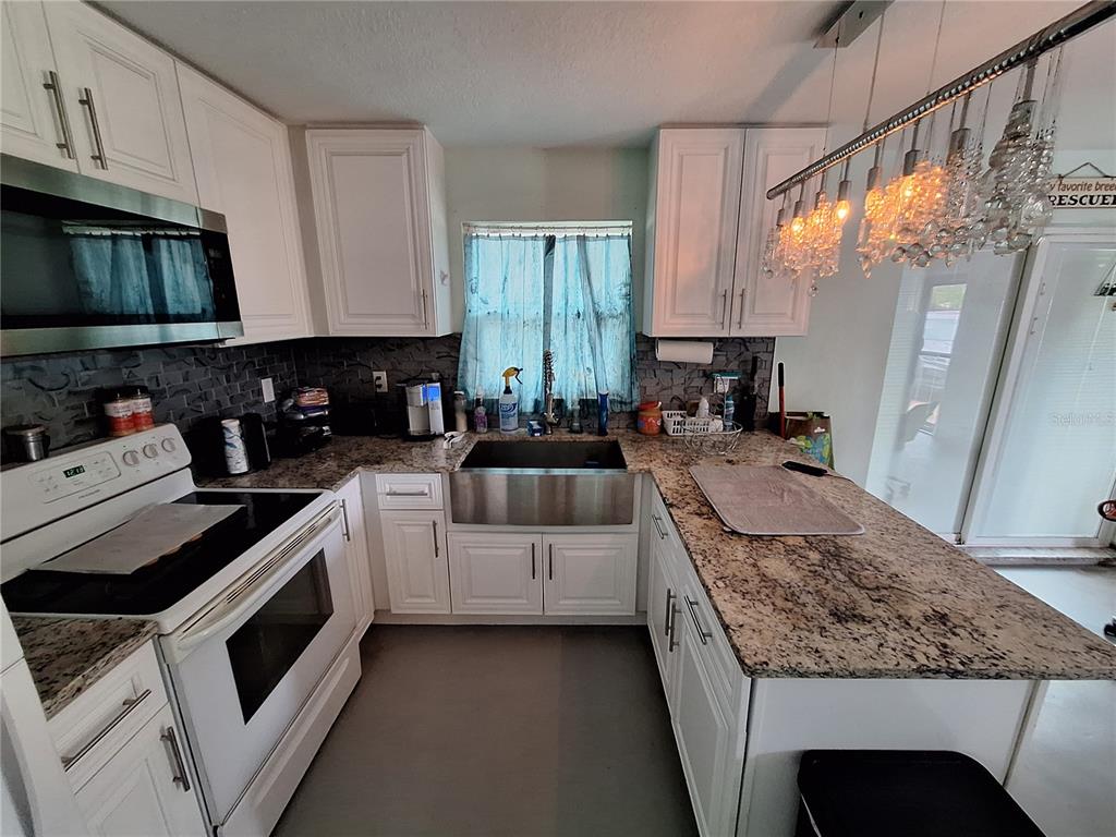 9415 Indale Drive New Port Richey, FL 34654 - Photo 68 of 93 a kitchen with stainless steel appliances granite countertop a stove a sink and a microwave
