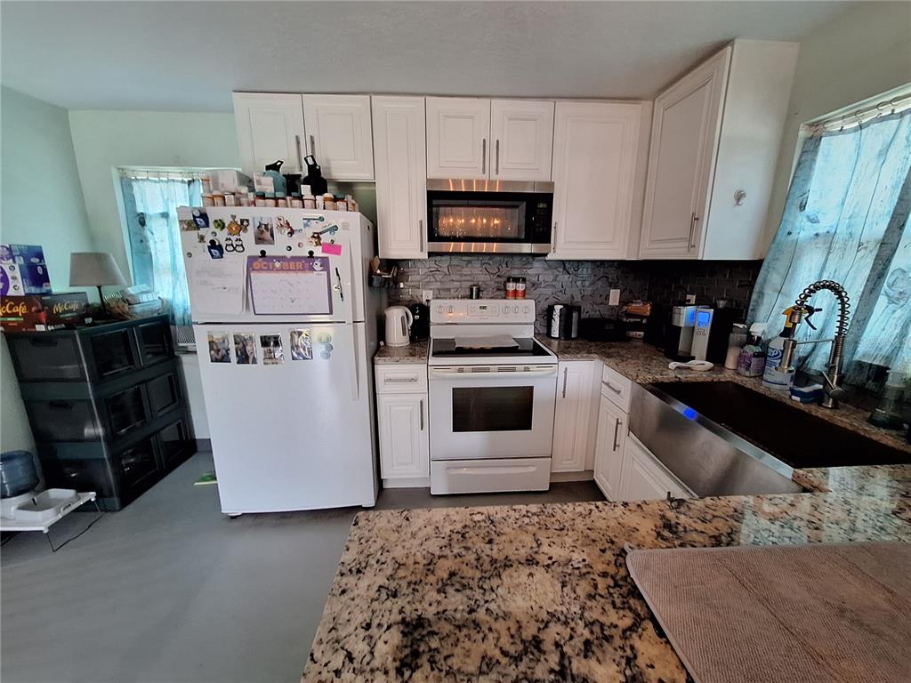 9415 Indale Drive New Port Richey, FL 34654 - Photo 69 of 93 a kitchen with a sink refrigerator and microwave
