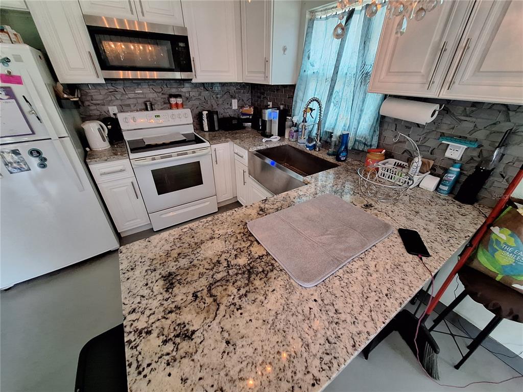 9415 Indale Drive New Port Richey, FL 34654 - Photo 70 of 93 a kitchen with stainless steel appliances granite countertop a sink a stove a microwave a refrigerator and cabinets