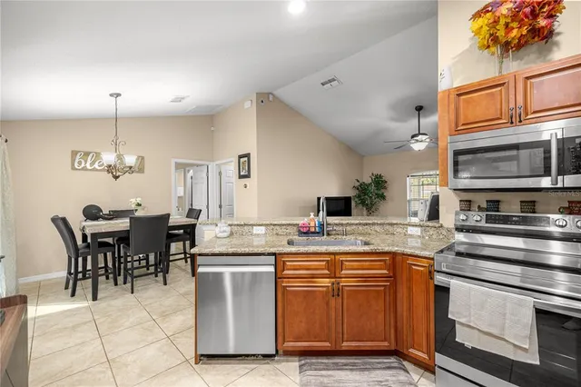 a kitchen with stainless steel appliances granite countertop a stove top oven a sink dishwasher and white cabinets
