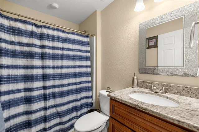 a bathroom with a granite countertop sink and a toilet