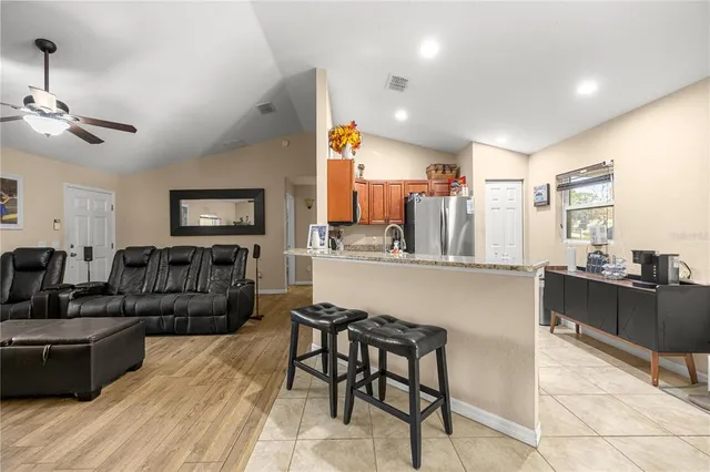 a living room with furniture a flat screen tv and kitchen view