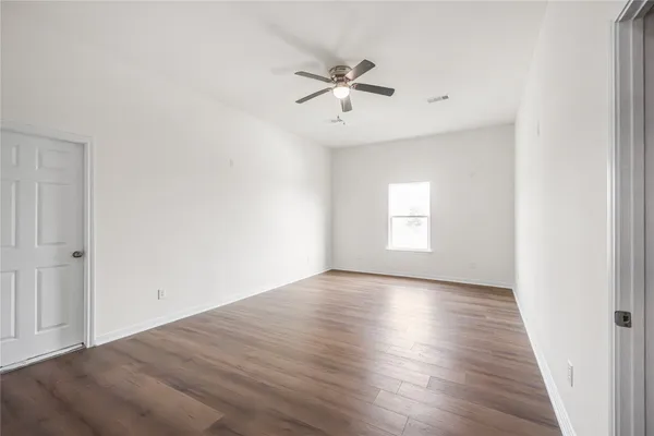 an empty room with wooden floor window and ceiling fan
